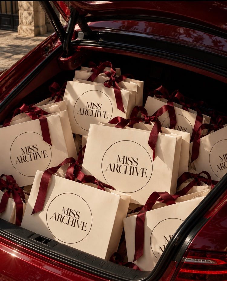 A car boot filled with MISS ARCHIVE gift bags tied with burgundy ribbon